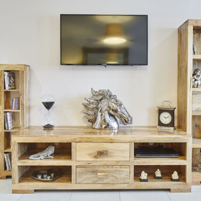 a television is mounted on the wall above a wooden entertainment center with drawers and shelves