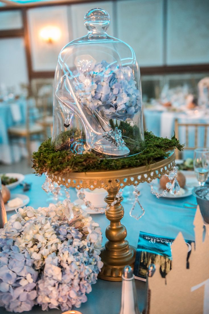 a table topped with a glass clochet covered in flowers