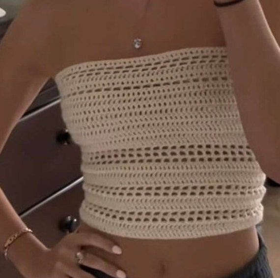 a woman is taking a selfie in the mirror with her cell phone while wearing a white crochet crop top