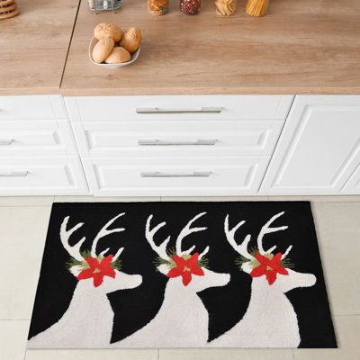 three reindeer heads with red bows on their antlers in front of a kitchen counter