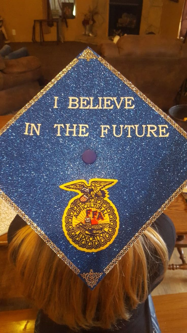 a woman wearing a blue graduation cap with the words i believe in the future on it