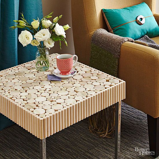 a coffee table with flowers in a vase on it next to a chair and window