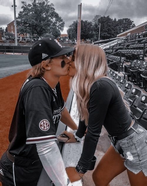 two women kissing each other at a baseball game