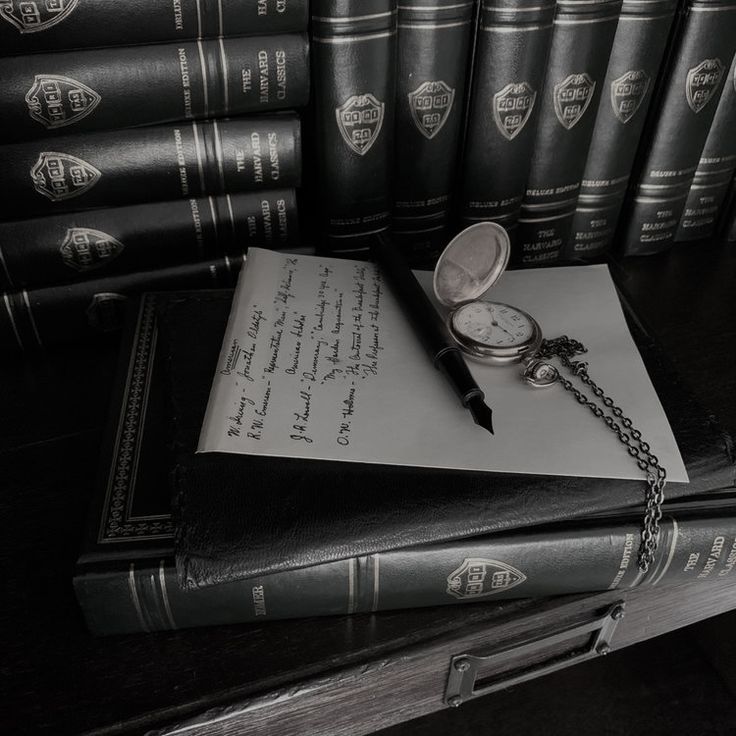 a stack of books sitting on top of a table next to a pocket watch and pen