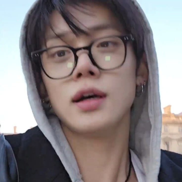 a young man wearing glasses and a hoodie