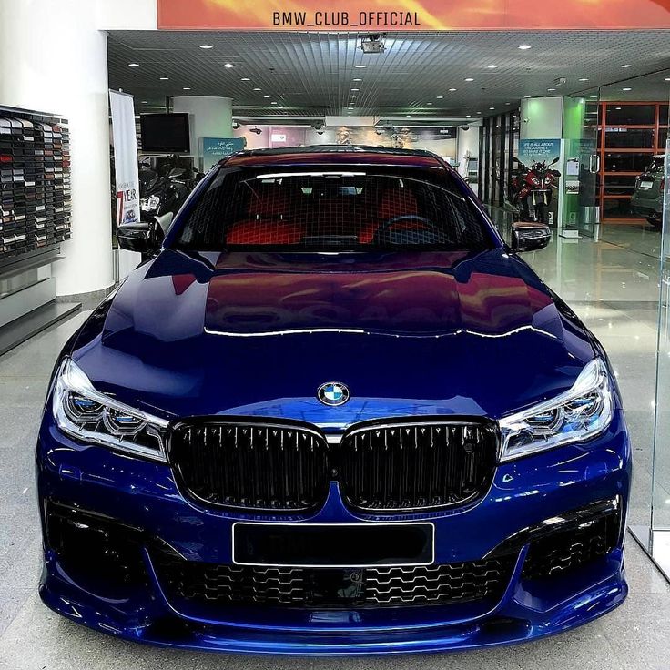 a blue car parked in front of a bmw showroom