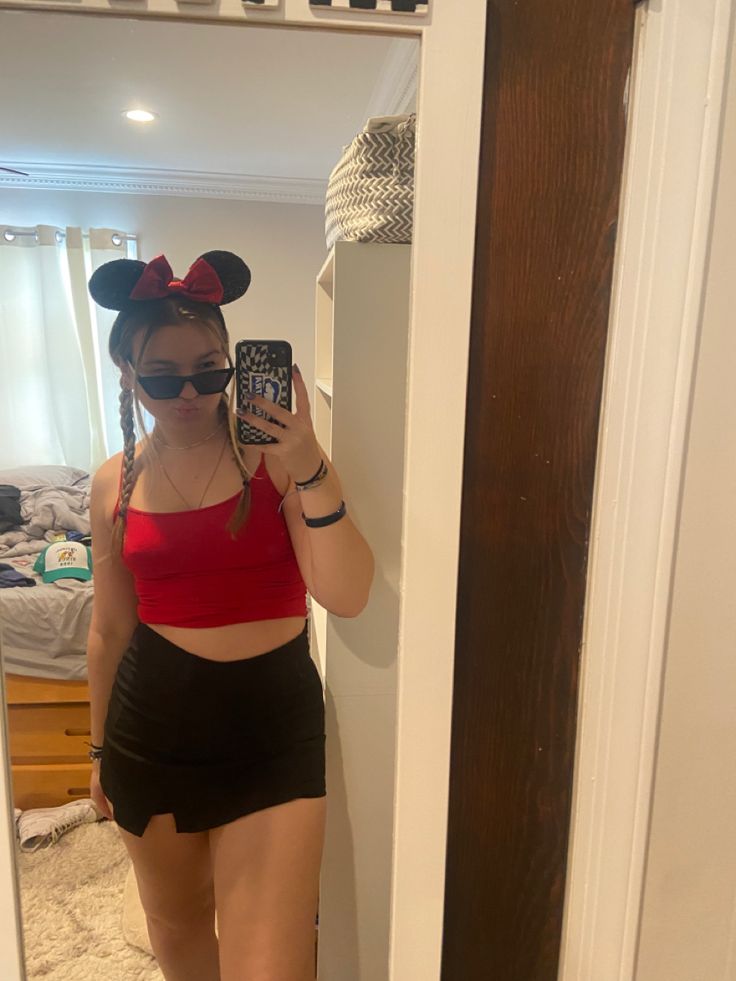 a woman taking a selfie in front of a mirror with minnie mouse ears on her head