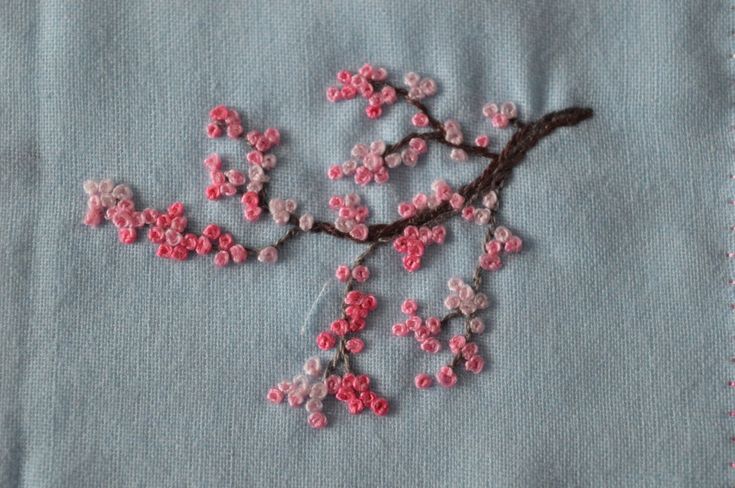 a close up of a piece of cloth with pink flowers on it and a branch