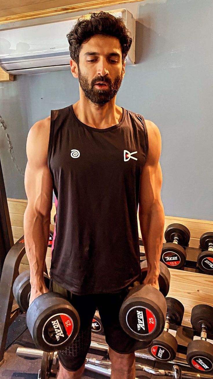 a man standing in front of a row of dumbbells