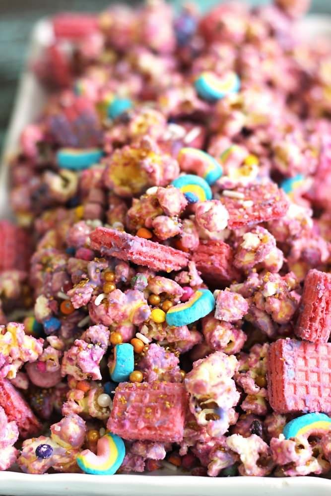 a white plate filled with pink cereal and candy corn mix on top of a wooden table