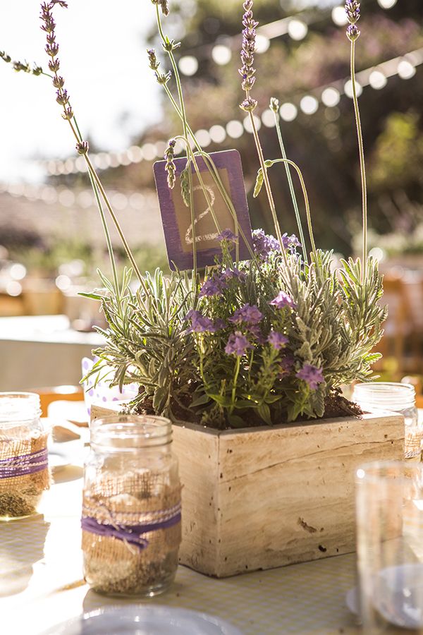 an outdoor table setting with lavenders and herbs in mason jars on the table top