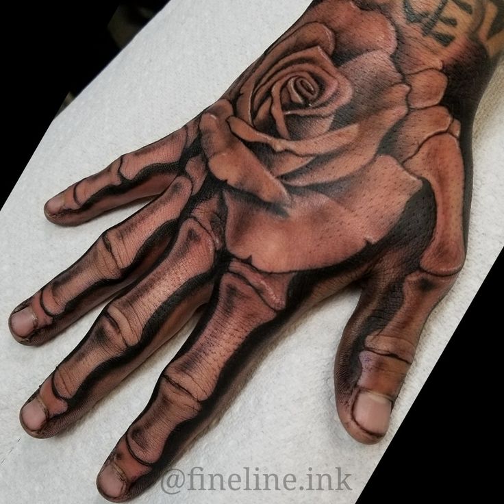 a person's hand with a rose tattoo on it