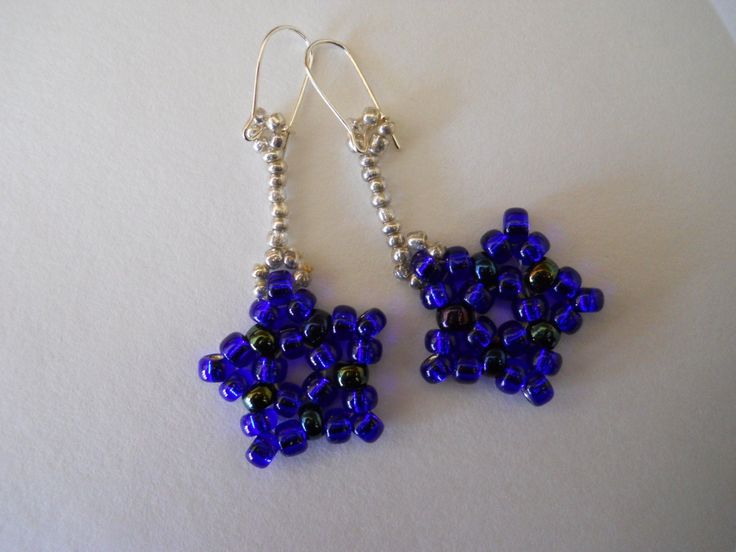 a pair of blue beaded earrings sitting on top of a white table next to each other