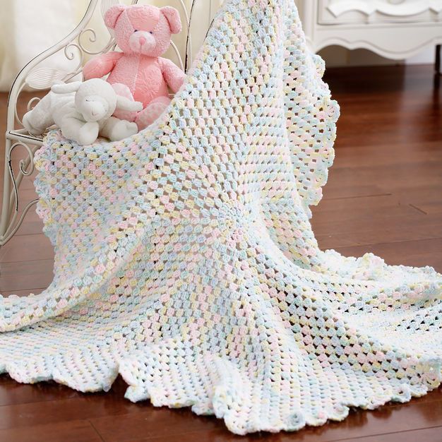 a crocheted blanket with a pink teddy bear in it on a white chair