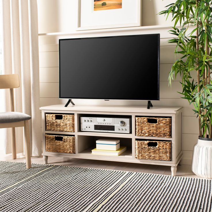 a flat screen tv sitting on top of a wooden entertainment center next to a potted plant