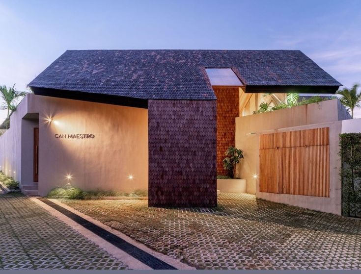 a house that has a brick driveway in front of it and lights on the side