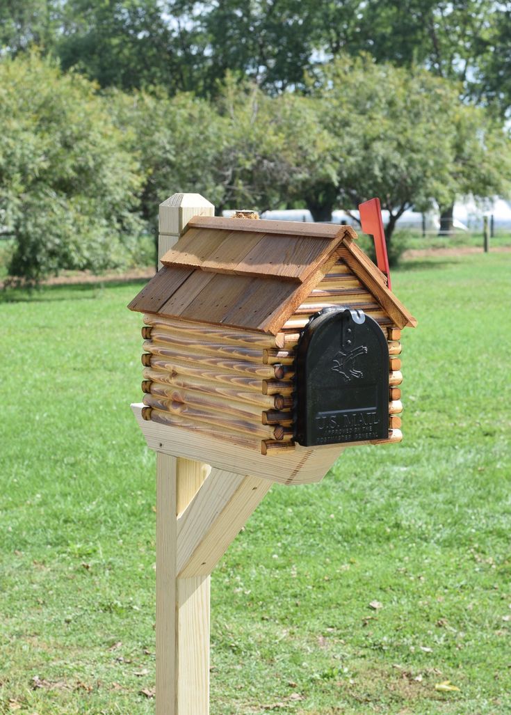 a wooden mailbox sitting in the middle of a field