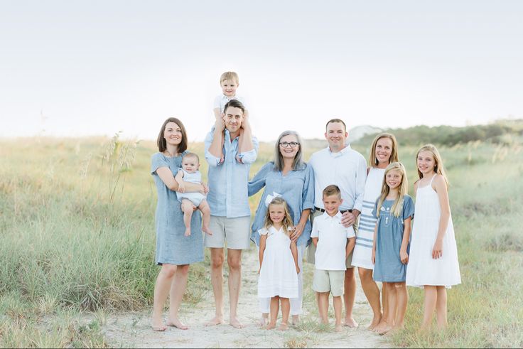 a family posing for a photo on the beach in front of grass and sand dunes