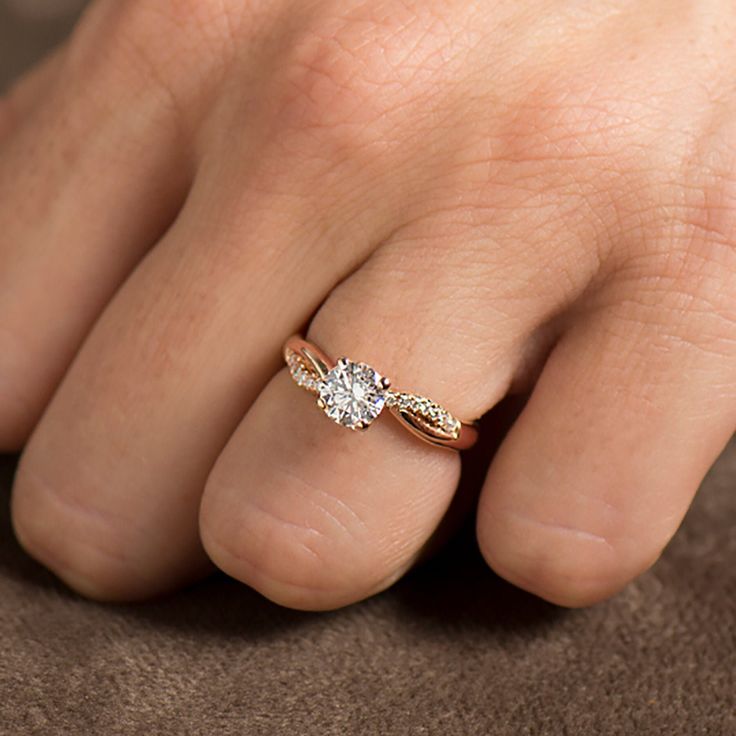 a close up of a person's hand with a diamond ring on their finger