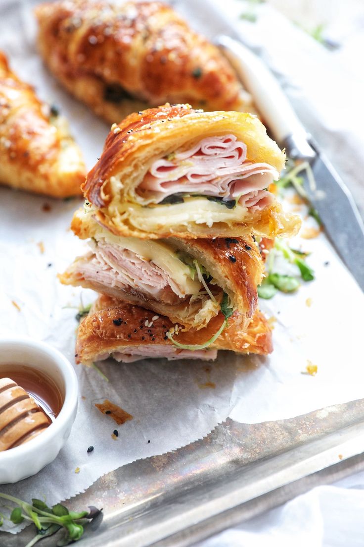 a sandwich cut in half sitting on top of a cutting board next to a small bowl of dipping sauce