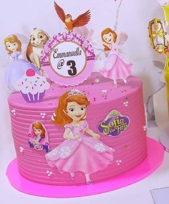 there is a pink cake decorated with princesses and cupcakes on the top