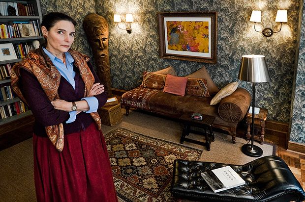 a woman standing in a living room next to a couch and book shelf filled with books