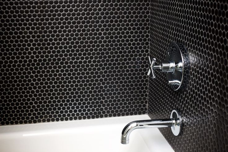 a white bath tub sitting under a faucet next to a black and white wall