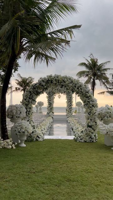 an outdoor ceremony setup with white flowers and greenery on the grass near the water