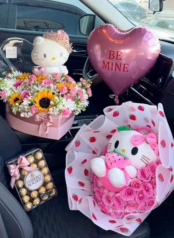 hello kitty cake in the back seat of a car with balloons and flowers on it