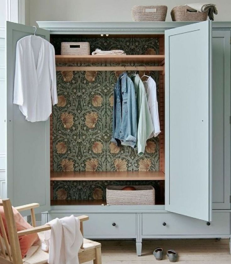 an open closet with clothes hanging on the wall and a chair in front of it