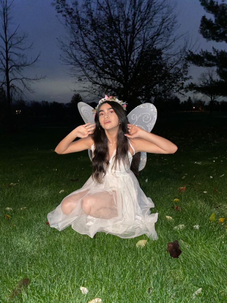 a woman dressed as a fairy sitting in the grass