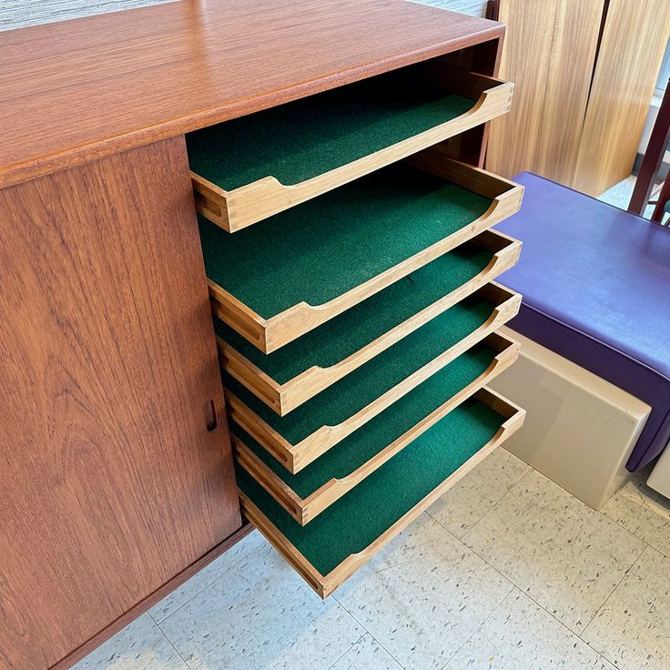 a large wooden cabinet with many drawers on it's sides and a blue chair in the background