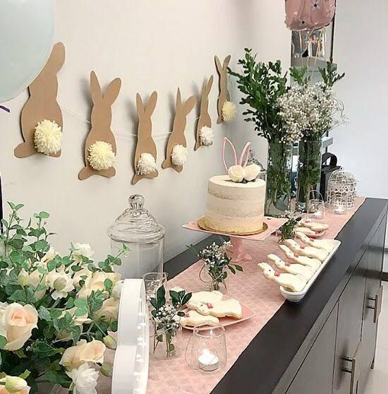 a table topped with cake and flowers next to bunnies on the wall behind it