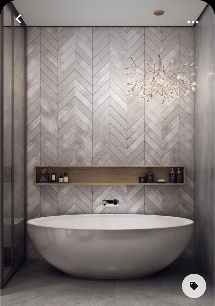 a large white bath tub sitting next to a wooden shelf in a bathroom with herringbone tiles on the walls