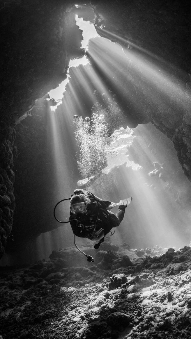 a person diving in the water with sunbeams