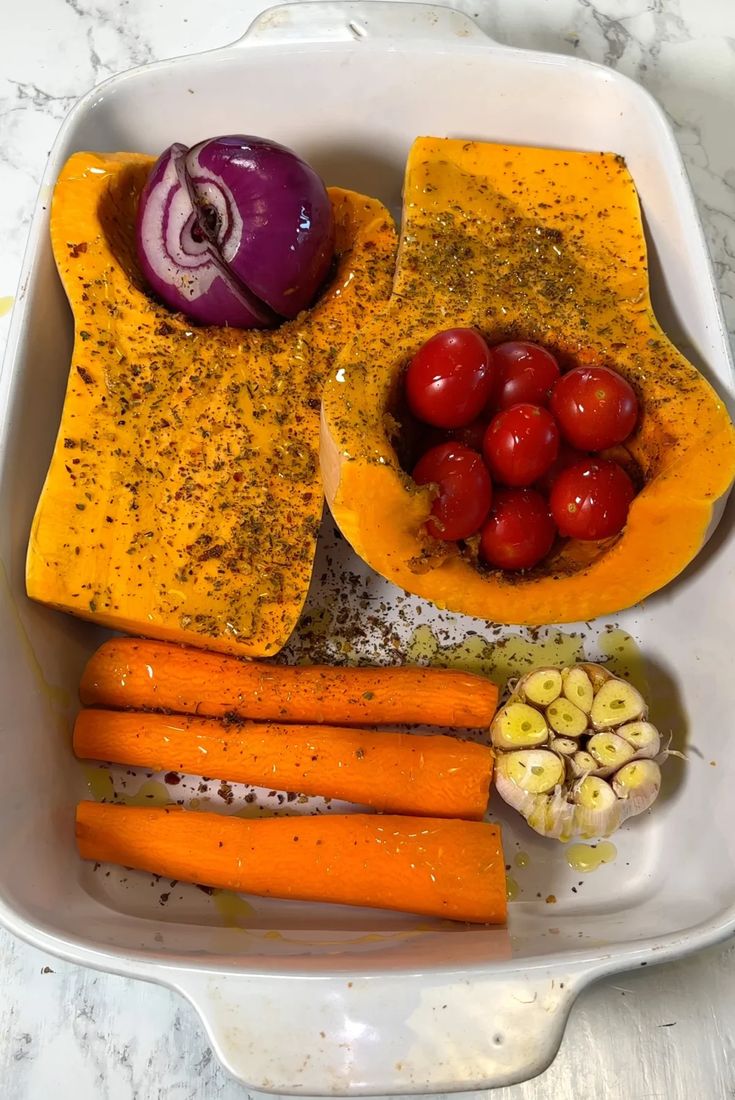 carrots, tomatoes and other vegetables are in a white dish on a marble table