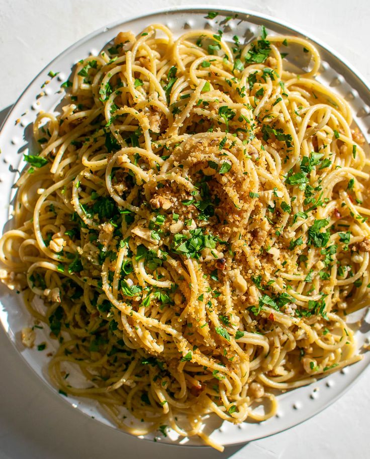 a white plate topped with pasta covered in sauce and parsley