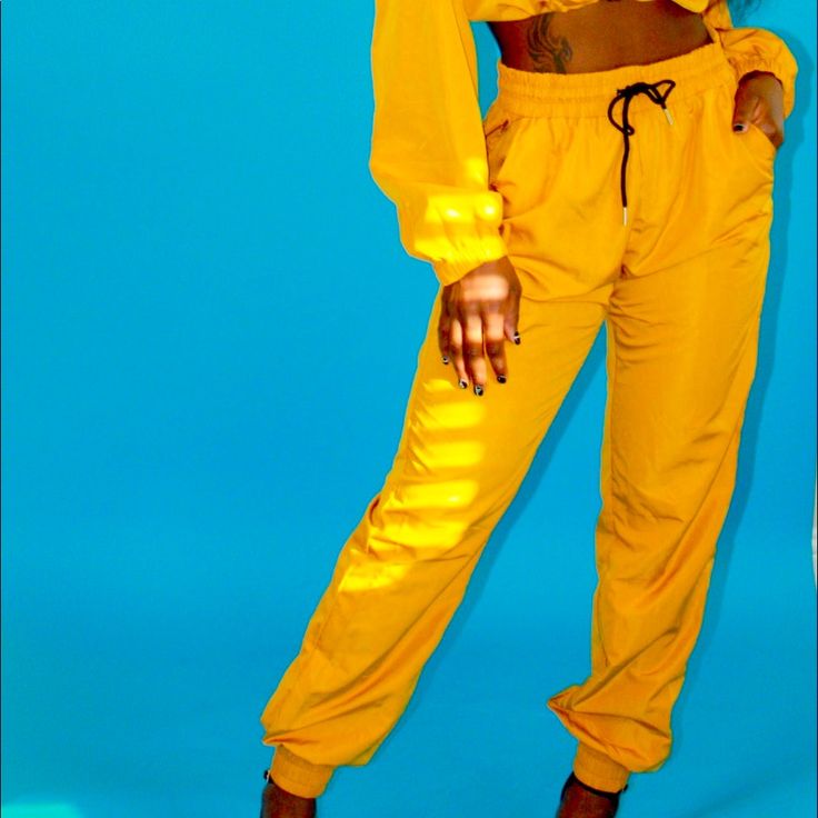 These Jogger-Style Pants Are Perfect For Every Season. They're Super Lightweight With Pockets Of Course. The Adjustable Drawstring And Elastic Waist Will Provide You With Custom Comfort. The Windbreaker Feel Will Make The Great For The Transitioning Weather Between Every Season. Yellow Fitted Jumpsuits And Rompers With Pockets, Mustard Fitted Casual Jumpsuits And Rompers, Fitted Yellow Jumpsuits And Rompers With Pockets, Trendy Yellow Pants With Pockets, Stretch Yellow Pants With Pockets, Yellow Stretch Pants With Pockets, Yellow Bottoms With Pockets For Loungewear, Yellow Loungewear Bottoms With Pockets, Yellow Pants With Elastic Waistband For Streetwear