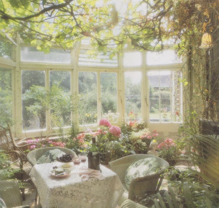 a table and some chairs in a room with flowers on the window sills