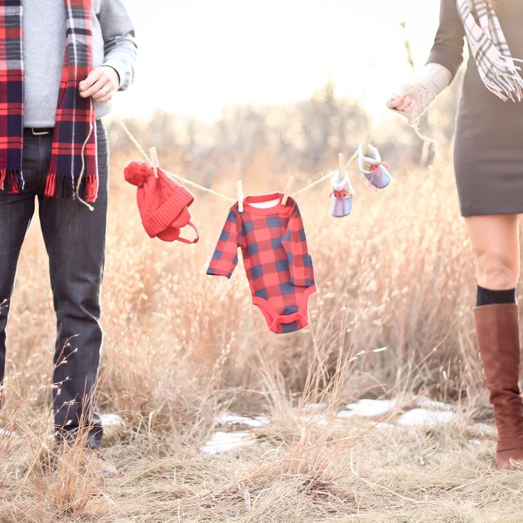 two people are standing in the grass with clothes hanging on a line and one person is wearing boots