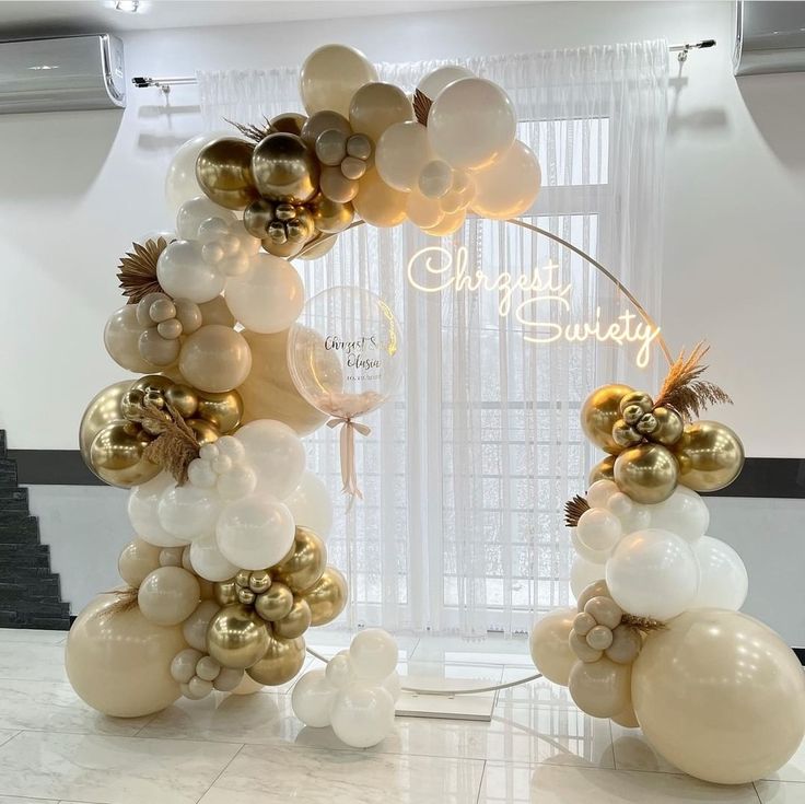 balloons are arranged in the shape of an arch with gold and white balls on it