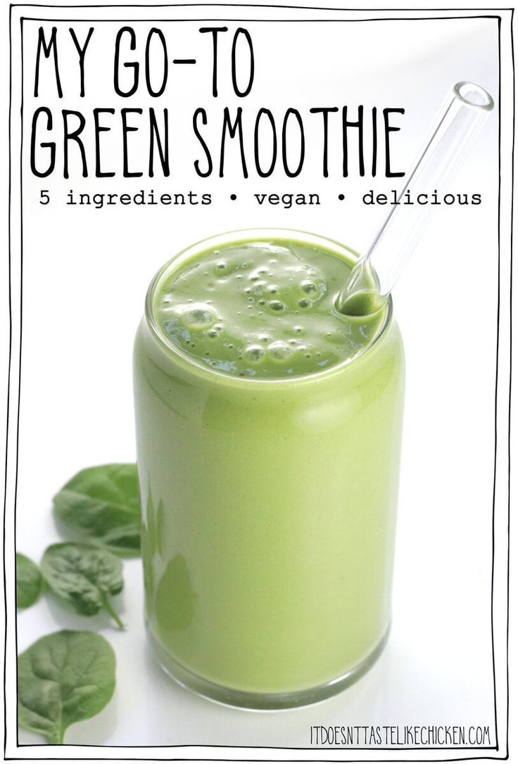 a green smoothie in a glass with a straw on top and leaves around it