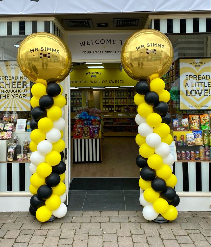 two large balloons are in front of a store with black and white stripes on it