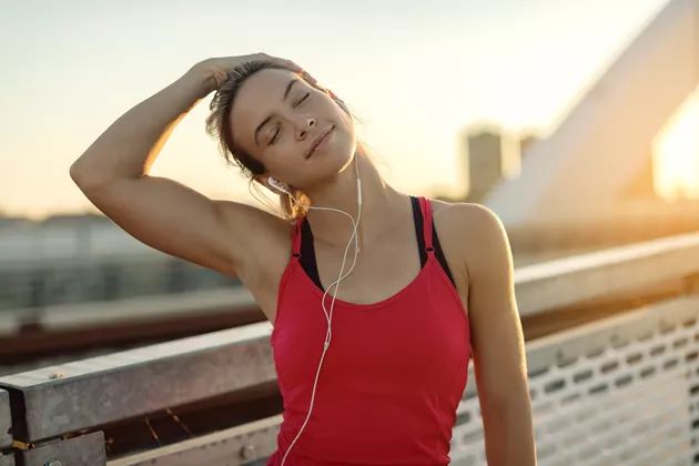 a young woman listening to music on her headphones while sitting on a bench in the sun