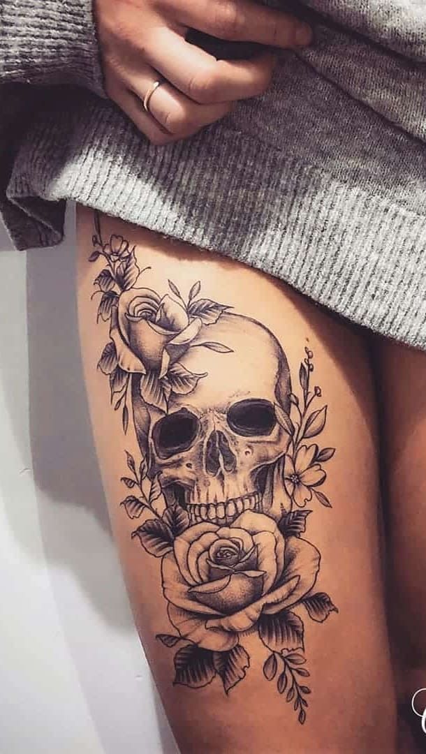 a woman's thigh with a skull and roses tattoo on it