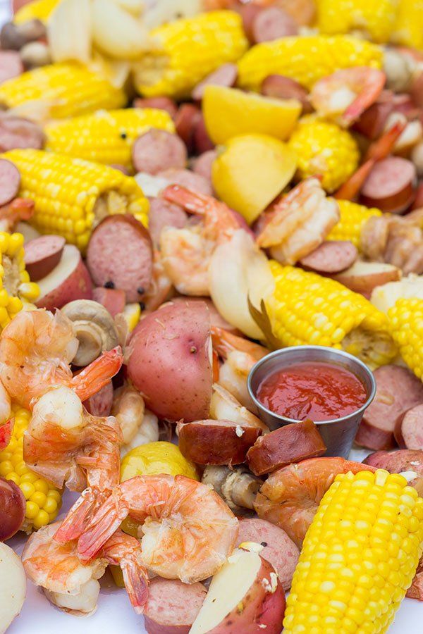 corn on the cob, potatoes, and sausages are being prepared to be eaten