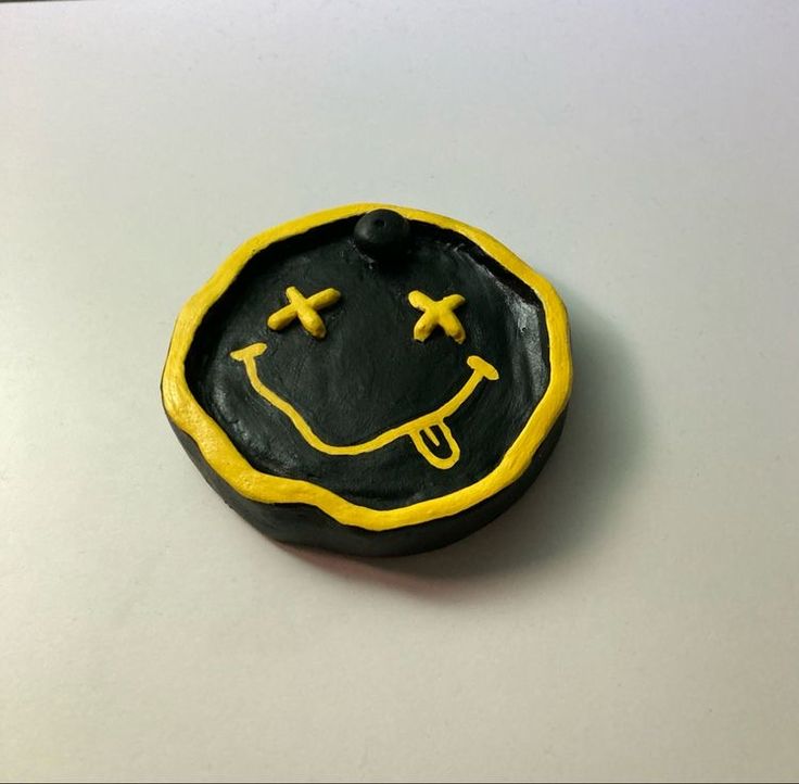 a black and yellow plate with a smiley face on the side, sitting on a white surface