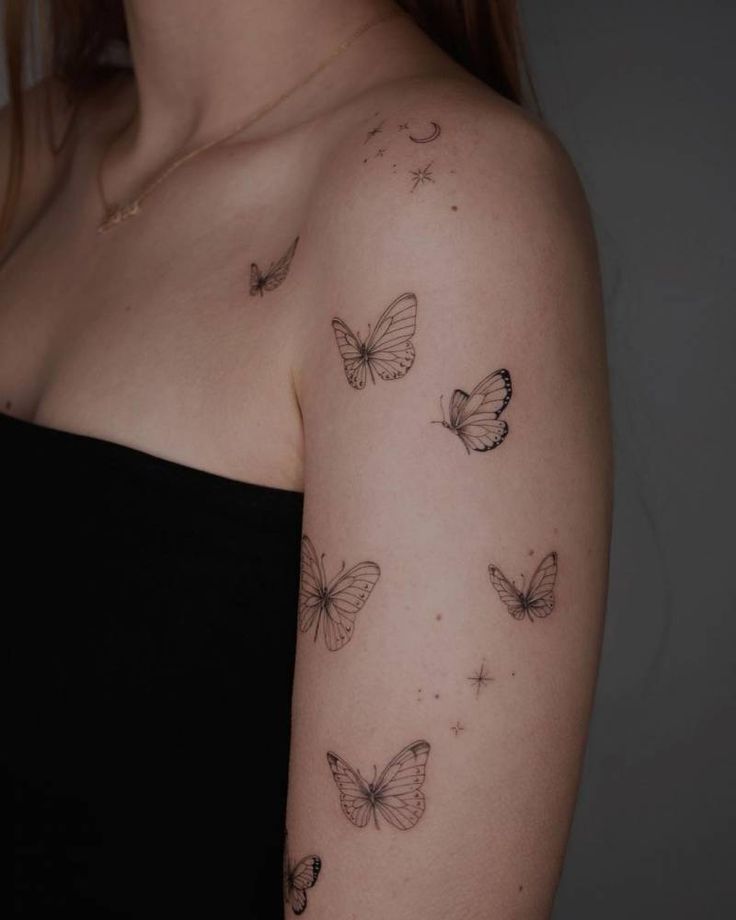 a woman's arm with butterflies and stars tattooed on the back of her shoulder