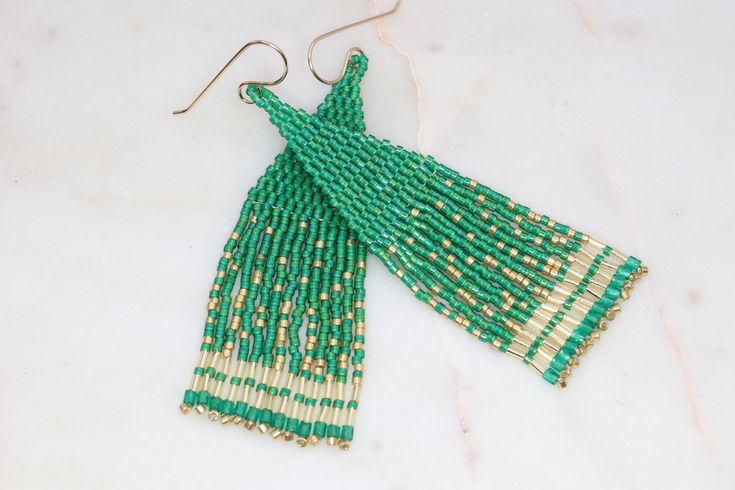 Handmade artisan boho chandelier earrings in the most gorgeous shades of emerald green and gold with gently swaying fringe. Each tiny bead is selected and hand sewn into place, one at a time with a needle and thread. No plastics, no glue, no looms - completely hand stitched with strong nylon thread.Ear wires are gold filled.Lightweight and comfortable, these earrings make a great gift or stocking stuffer for that special woman or a treat for yourself. All our items ship boxed and ready to gift. Emerald Green And Gold, Boho Chandelier, Handmade Earrings Beaded, Beaded Hoops, Unique Gifts For Her, Crystal Charm, Seed Bead Earrings, Birthstone Charms, Seed Bead Jewelry