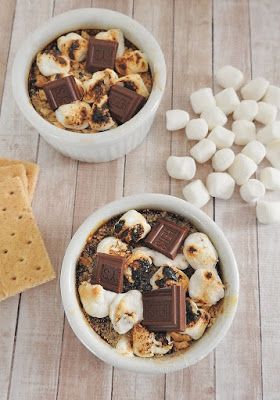 two bowls filled with marshmallows and chocolate on top of a wooden table